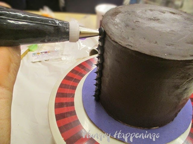 piping chocolate frosting dots on a chocolate cake. 