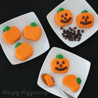 mini cheesecake pumpkins decorated with chocolate chips to look like Jack-O-Lanterns