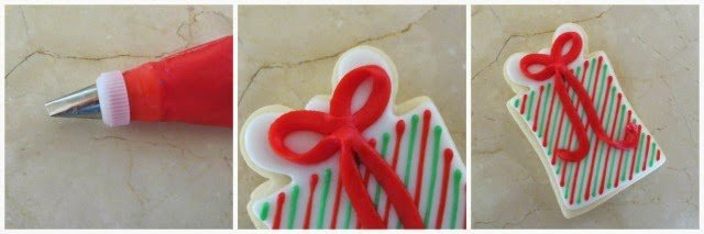 adding a red frosting bow on the Christmas present cookies.