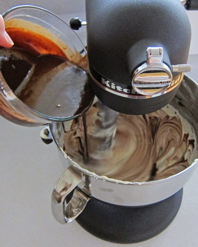 pouring chocolate ganache into the cheesecake filling. 