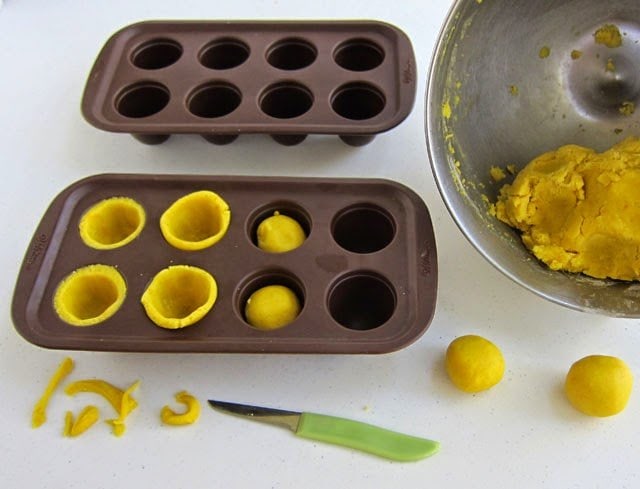 yellow balls of cookie dough are shaped into corn on the cob in brownie pops molds. 