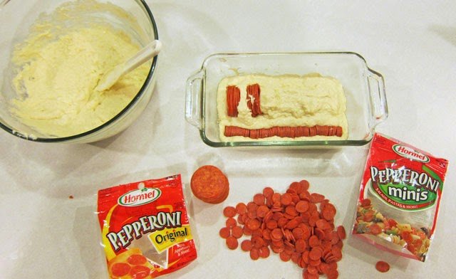 adding rows of mini and regular pepperoni to bread dough in a loaf pan. 