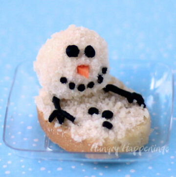 Melting Snowman Cheese Balls with olive eyes, carrot nose, and black cream cheese buttons.