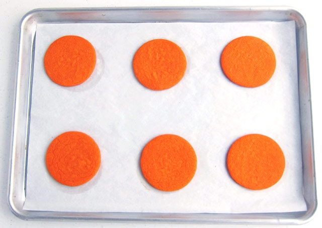 cutting out circles from orange cookie dough to make basketball cookies