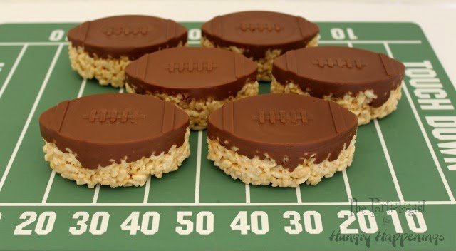 It's wouldn't be a Super Bowl party without them. Hi, it's Kim, The Partiologist back with another game day favorite. I don't think I've ever been to a super bowl party with out seeing a rice krispie treat and these Chocolate Topped Rice Krispie Treat Footballs are so simple and impressive! You can have them ready before kick off!