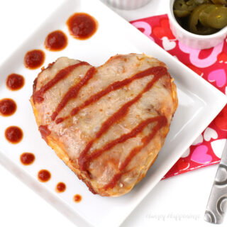 heart-shaped chicken enchiladas topped with cheese and chili sauce served with jalapenos and sour cream