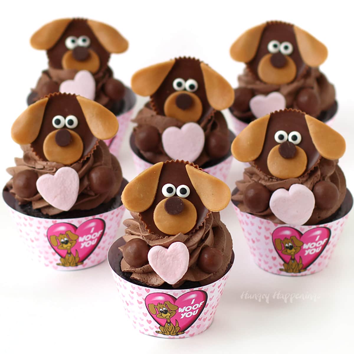 Cute chocolate dog cupcakes topped with Reese's Cups and candy hearts are wrapped in "I Woof You" cupcake wrappers for Valentine's Day