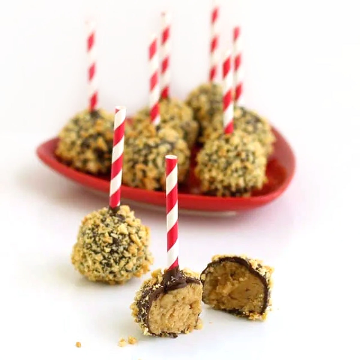 chocolate-dipped peanut-coated peanut butter potato candy on red and white striped lollipop sticks