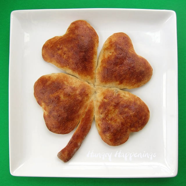 4 leaf clover breakfast sausage pizza on a white platter with a green background