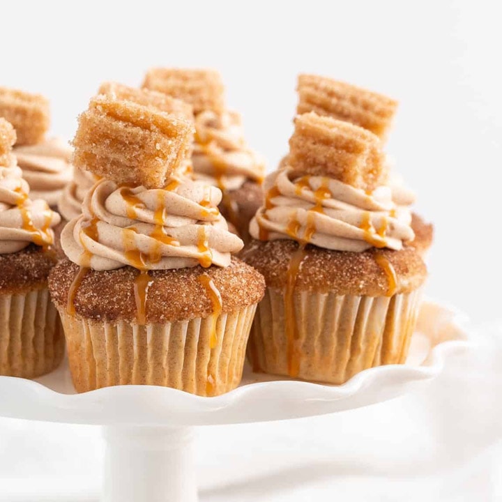 Churro Cupcakes topped with cream cheese frosting an a small churro