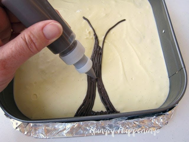 piping chocolate tree trunk onto the top of an un-baked cheesecake