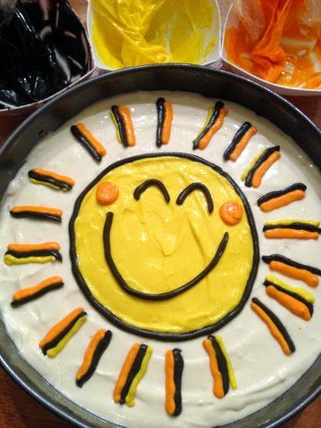 decorated cheesecake with a smiley face sunshine on top. 