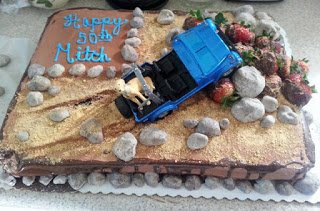 beach cake topped with a car running into a pile of rocks. 
