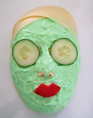 face mask cheese ball topped with green sour cream, cucumbers, and red pepper lips. 