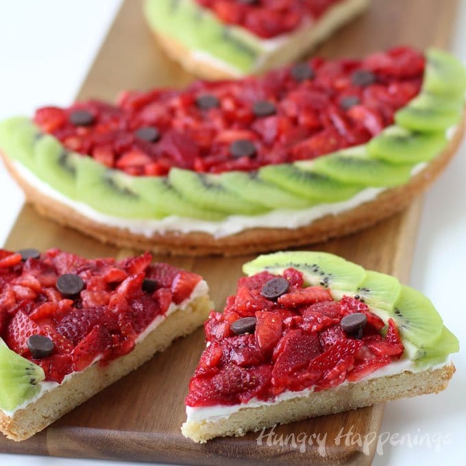 Want a fun summer dessert to serve at a pool party or picnic? This clever Strawberry Kiwi Fruit Pizza Watermelon is sure to WOW! Recipe at HungryHappenings.com