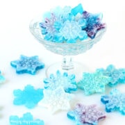 blue and white hard candy snowflakes arranged in a glass candy dish and on the white table.