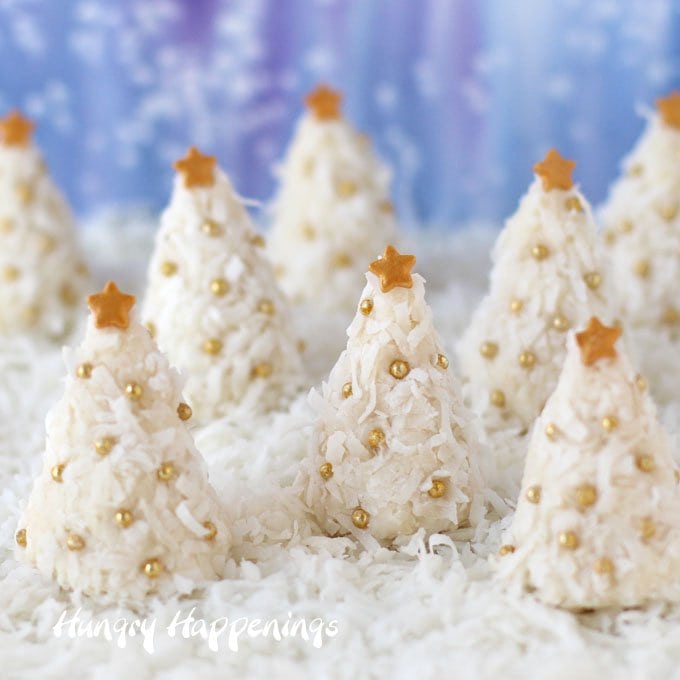 Coconut Cream Candy Christmas Trees arranged on a bed of coconut with a snowy blue background. 