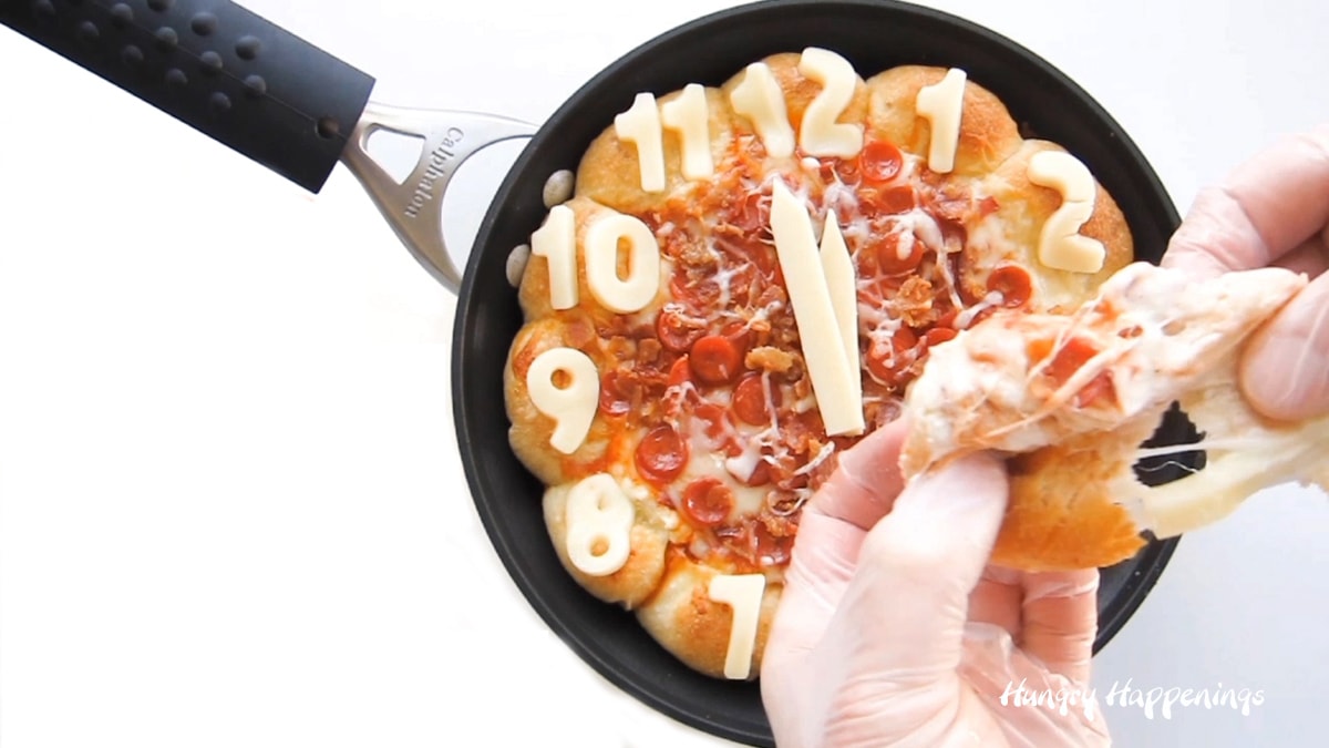 Pulling apart a cheese-filled pizza puff from a Skillet Pizza Dip clock.