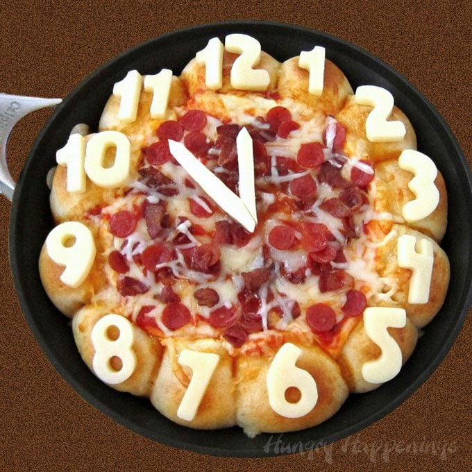 Ring in the New Year's by serving this cheesy Skillet Pizza Dip Countdown Clock loaded with pepperoni and bacon. The triple cheese dip is surrounded by 12 cheese filled pizza puffs each decorated with a number on a clock.