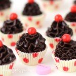 Cute little chocolate truffle cupcakes make sweet Valentine's Day treats. Each polka dot white chocolate cup is filled with a swirl of dark chocolate ganache and topped with a Sixlet. See how easy they are to make at HungryHappenings.com.