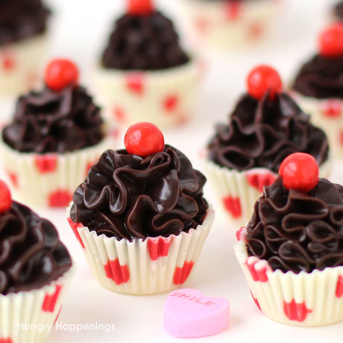 chocolate truffle cupcakes with red polka dot white chocolate cups filled with a swirl of chocolate ganache.