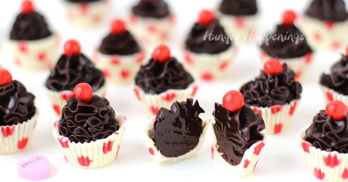 Cute little chocolate truffle cupcakes make sweet Valentine's Day treats. Each polka dot white chocolate cup is filled with a swirl of dark chocolate ganache and topped with a Sixlet. See how easy they are to make at HungryHappenings.com.