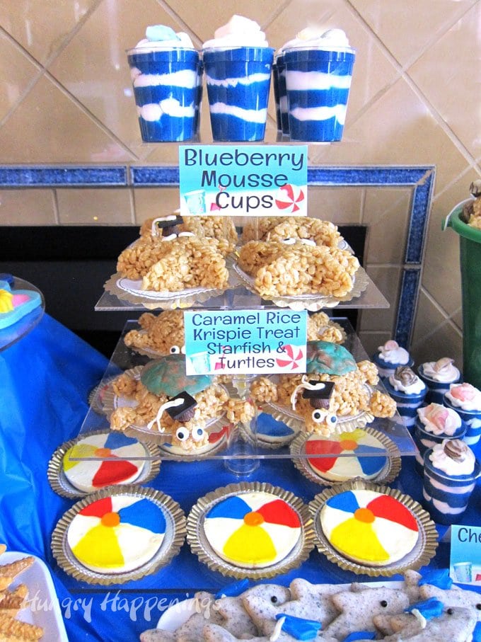  Beach themed party food including blueberry mousse cups, caramel rice krispie treat sea life, and beach ball cheesecakes.