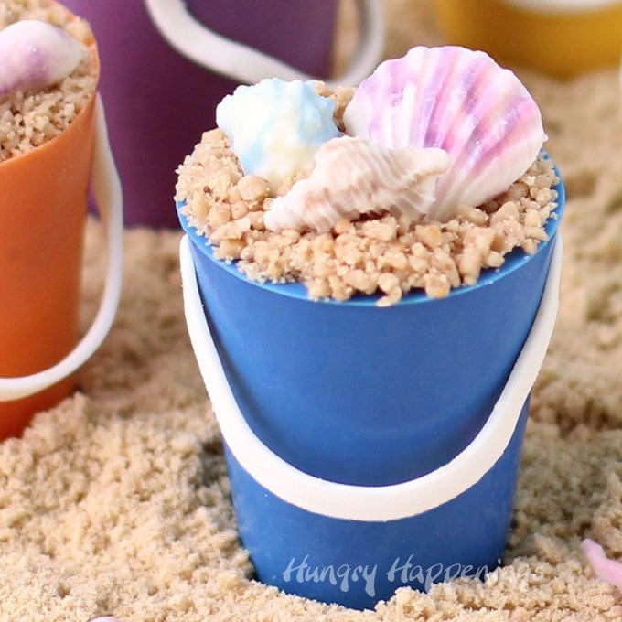 Turn little handmade chocolate cups into these adorable Mini Chocolate Beach Pails filled with Dulce de Leche Mousse and topped with toffee bits "sand" and chocolate shells. They will make great treats for your beach themed party.