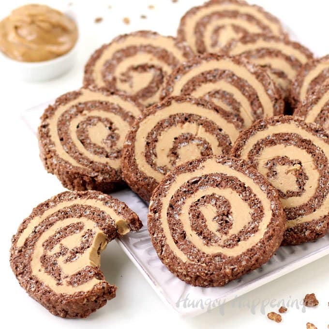 Turn ordinary rice krispie treats into festive Cocoa Crispy Treat Peanut Butter Fudge Pinwheels. Chocolate cereal treats are flattened and filled with peanut butter fudge then are rolled up and cut into pretty swirled pinwheels.