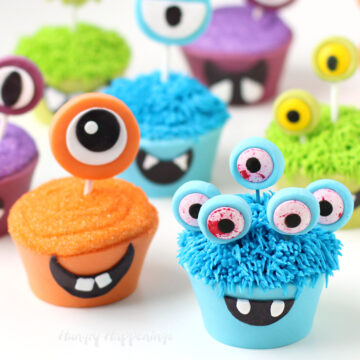 monster cupcakes wrapped in brightly colored candy clay decorated with big googly eyes and fangs.
