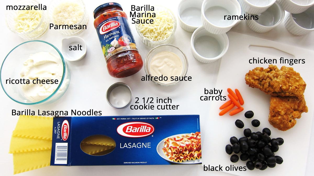 mini lasagna snowmen ingredients including 3 cheeses, lasagna noodles, 2 sauces, chicken fingers, carrots, and olives.