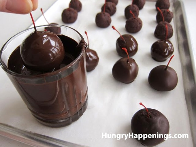 Dip a chocolate cake ball stuffed with a maraschino cherry into melted chocolate.