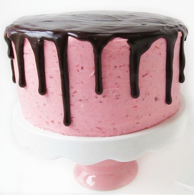 There is a surprise hiding inside this pretty pink cake which is frosted with strawberry cheesecake frosting and glazed with chocolate ganache.
