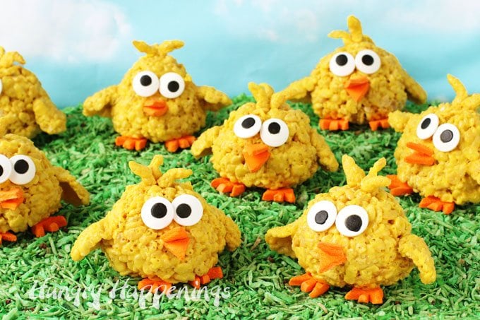 Bright yellow rice krispies treats are transformed into adorable little baby chicks for Easter with cereal treat wings and feathers and orange circus peanut feet and beaks and big candy eyes. 
