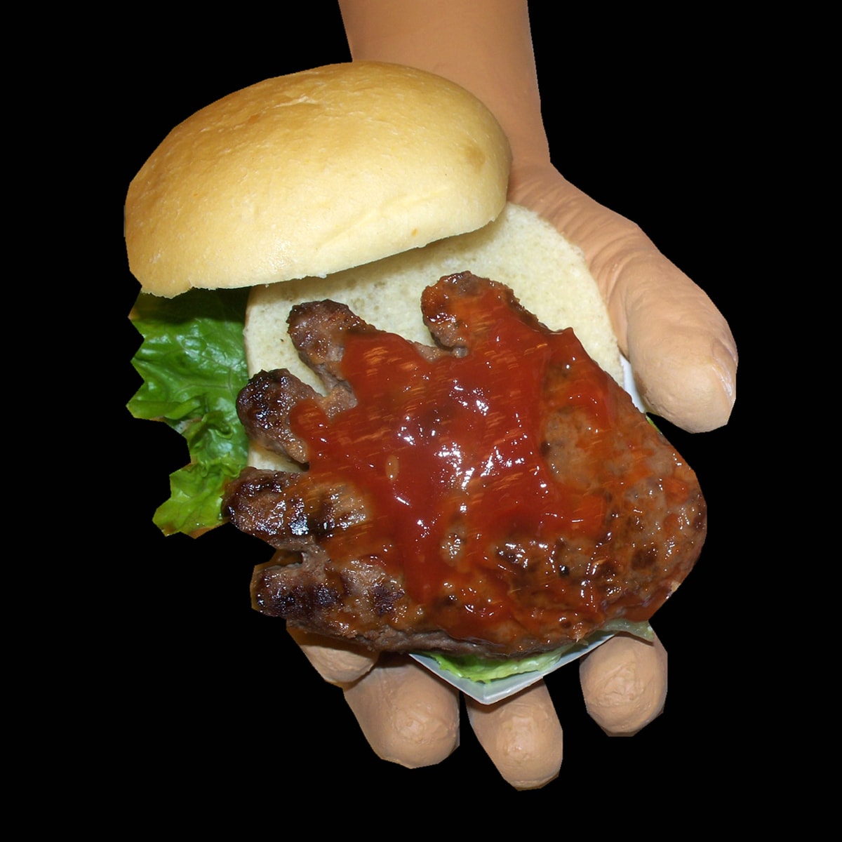 hand-shaped hamburger served on a small bun with lettuce and ketchup. 