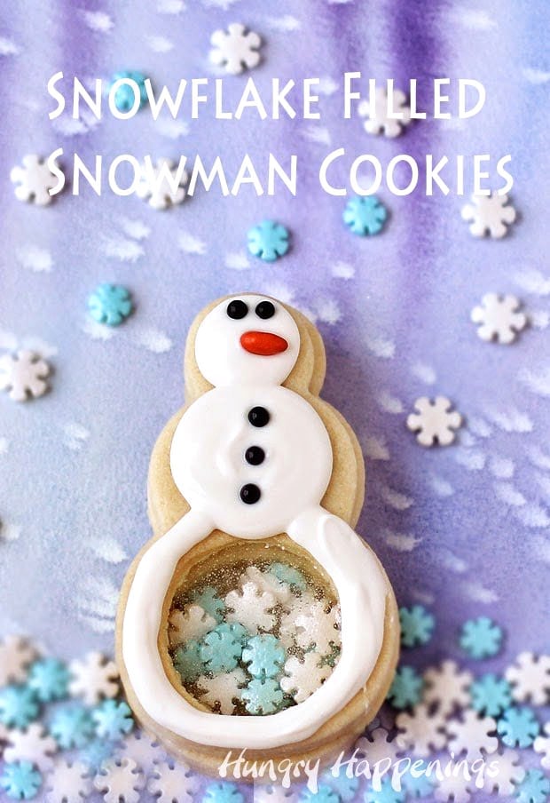 Snowman Cookies with clear candy windows in their bellies are filled with snowflake sprinkles and are decorated with white chocolate, black sugar pearls, and orange candy-coated sunflower seeds. 