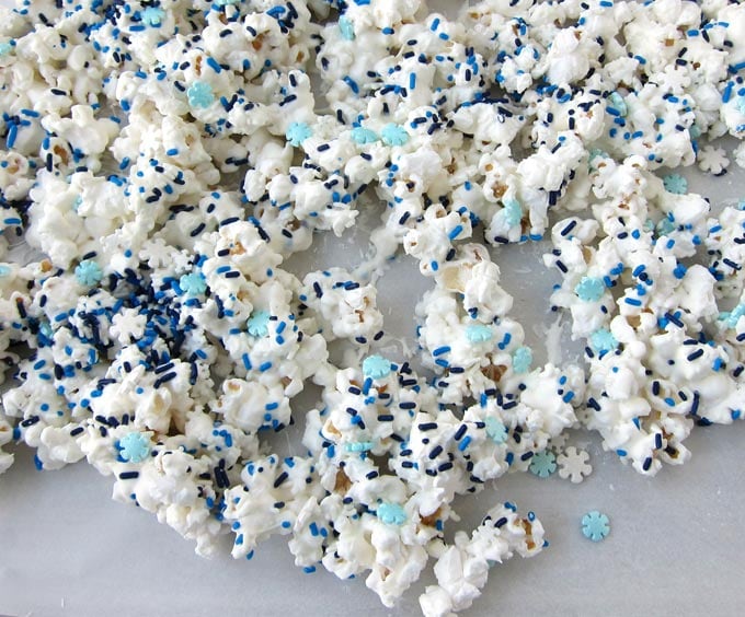 white chocolate popcorn sprinkled with candy snowflakes and blue and white jimmies