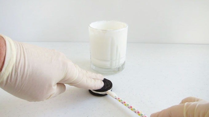 inserting a white chocolate dipped paper straw into an OREO cookie