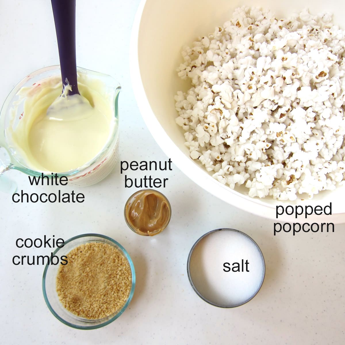 beach party popcorn ingredients including white chocolate, peanut butter, salt, cookie crumbs, and popcorn.