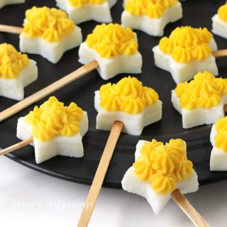 Deviled eggs cut using a star shaped cookie cutter are made into lollipops.