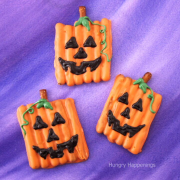 pumpkin pretzels decorated with Jack-O-Lantern faces.