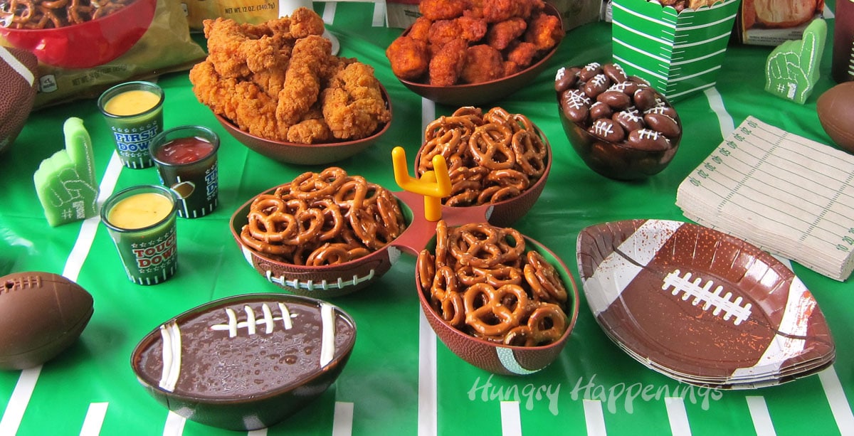 game day snacks including a chocolate football dip displayed on a football field tablecloth
