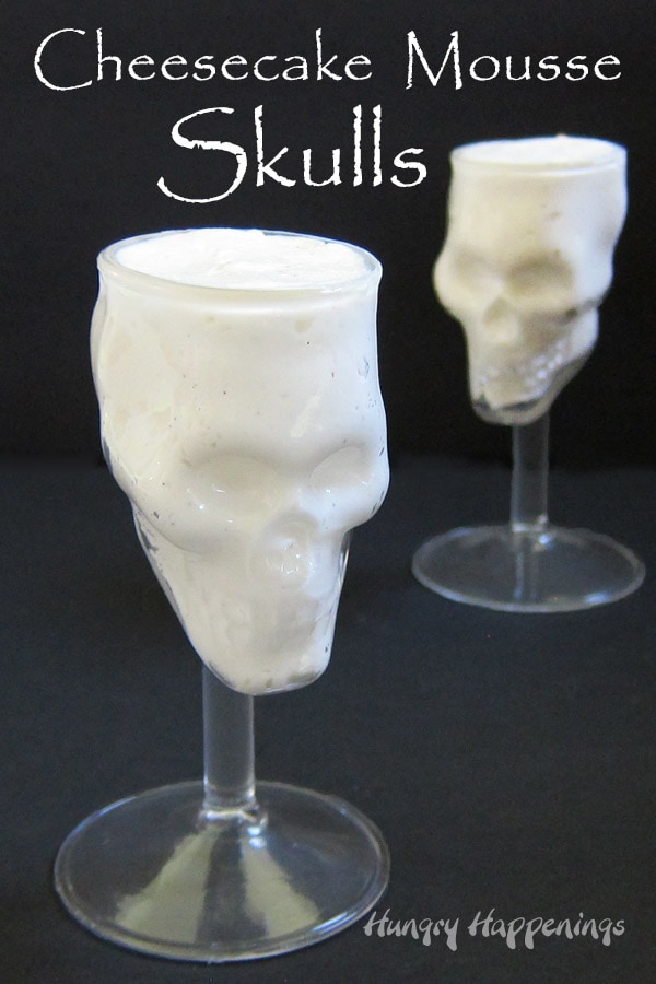 skull shaped wine glasses filled with no-bake cheesecake mousse on a black background with the phrase "cheesecake mousse skulls"