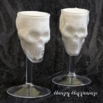 no-bake cheesecake served in skull shaped wine glasses displayed on a black watercolor background