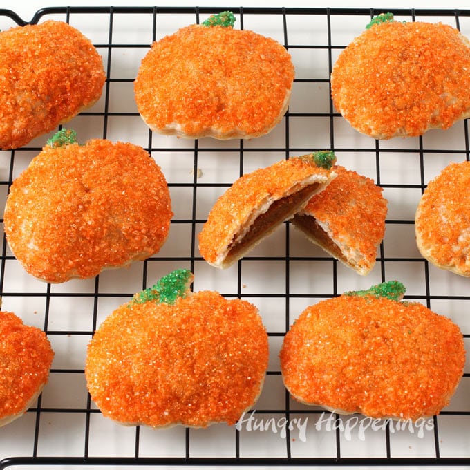 pumpkin hand pies coated in bright orange sugar set on top of a black wire cooling rack