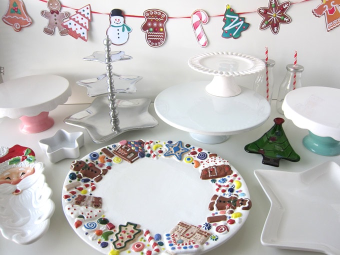 table filled with cookie platters, cake stands, and small Christmas dishes