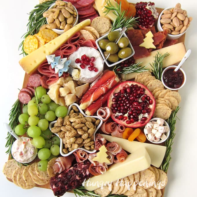 Holiday charcuterie board filled with meat, cheese, fruits, herbs, gourmet almonds and almond crackers. 