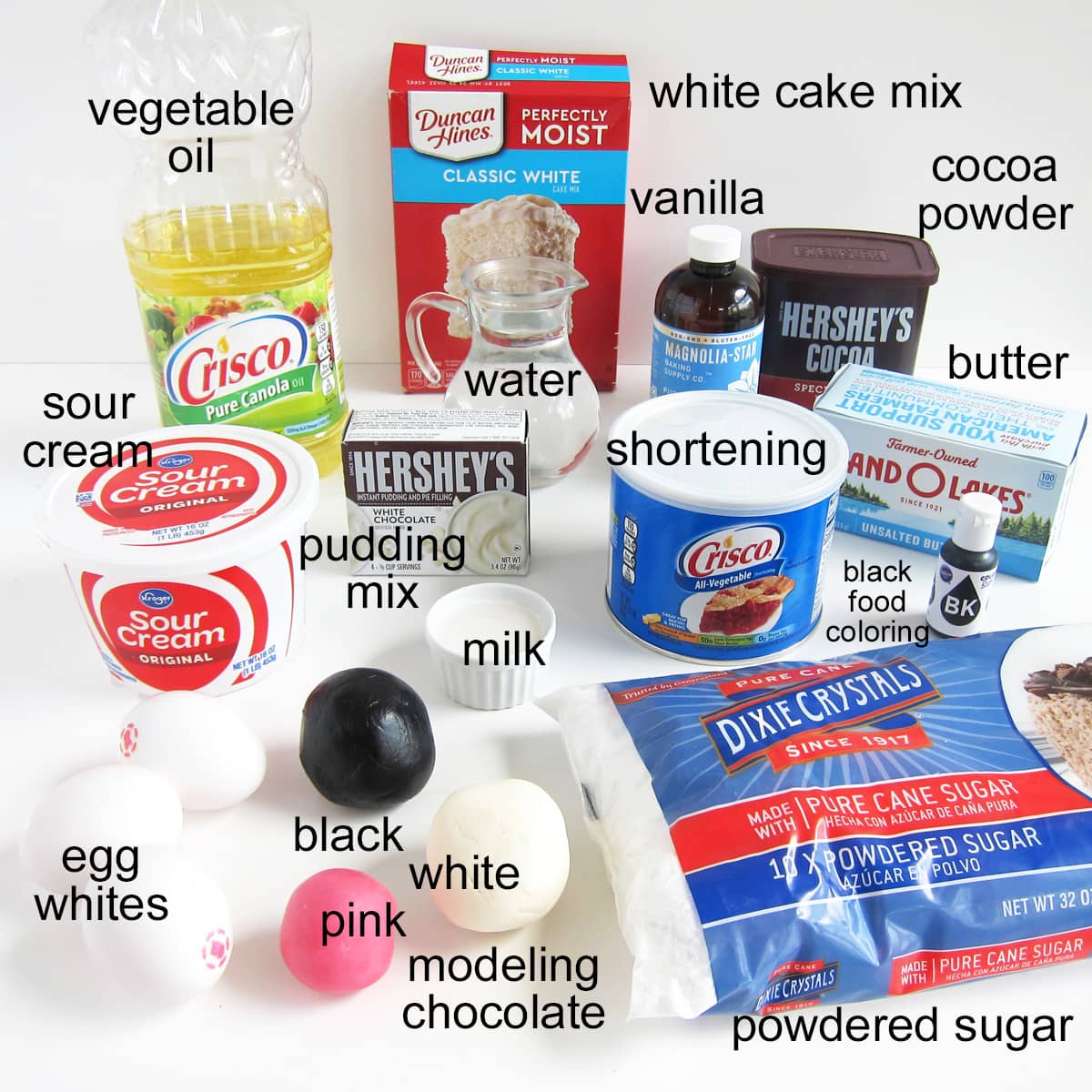 panda cake ingredients including white cake, oil, eggs, sour cream, pudding mix, powdered sugar, butter, shortening, vanilla, cocoa powder, milk, and modeling chocolate. 