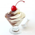 clear dessert cup filled with black and white mousse - a swirl of chocolate mousse and cheesecake mousse topped with a maraschino cherry