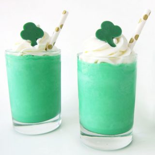 Shamrocks Shakes topped with a swirl of minty whipped cream and a green candy shamrock served with gold polka dot straws .